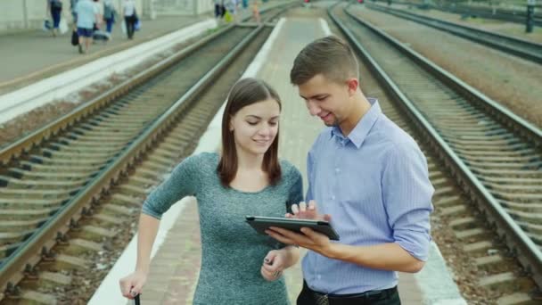 Viaje de negocios en tren. Un hombre y una mujer están de pie en una plataforma, usando una tableta — Vídeo de stock