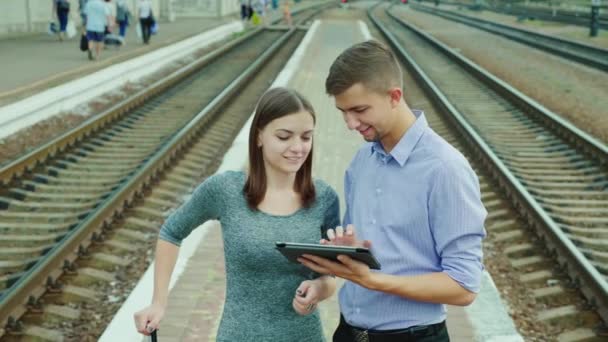 Geschäftsreise mit der Bahn. Ein Mann und eine Frau stehen mit einem Tablet auf einem Podest — Stockvideo