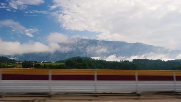 Вид из окна автомобиля на красивый альпийский пейзаж в Австрии. Автомобиль быстро проезжает мимо заграждения или забора — стоковое видео