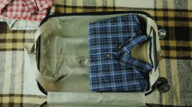 Bir adam bir bavul seyahat için paketleri. Yukarıdan görüntülemek