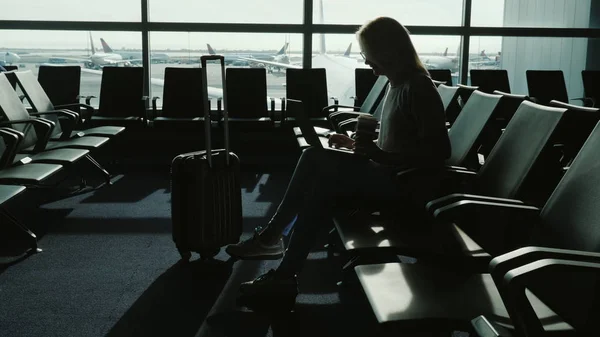 Woman enjoys laptop and drinks coffee at airport terminal — Stock Photo, Image