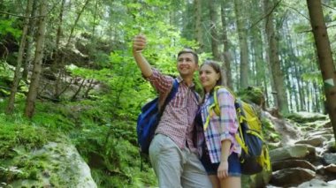 Turist çekici bir çift ormanda fotoğraflandı. Uzun bir yürüyüş üzerinde sırt çantaları ile Selfie