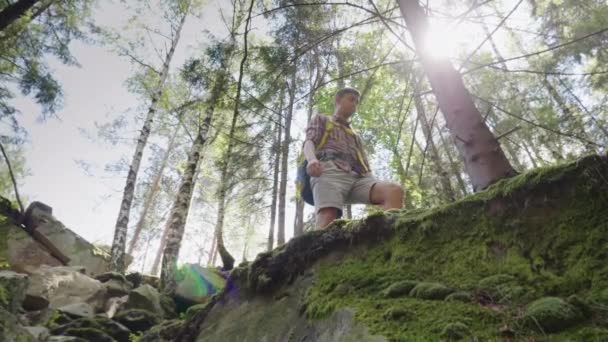 Een man met een rugzak achter hem in een wandeling. Lagere kijkhoek — Stockvideo