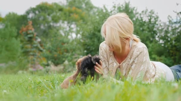 Žena hrající se dvěma štěňaty, ležící na trávníku v její zahradě — Stock video