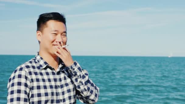 Chinese man rookt aan de kust — Stockvideo