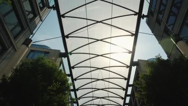 Стеклянный навес между зданиями для защиты от дождя и солнца. Комфорт в современном строительстве — стоковое видео