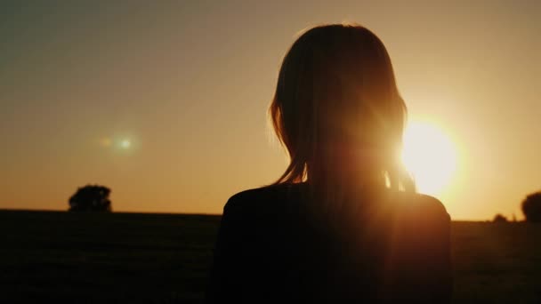 Uma mulher atenciosa olha para o pôr-do-sol, para a vista de trás. Sonhos e solidão conceito, olhar para a frente — Vídeo de Stock