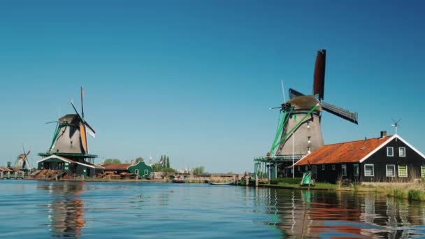 Schilderachtige landschap in Nederland - twee oude windmolens op de rivieroever — Stockvideo