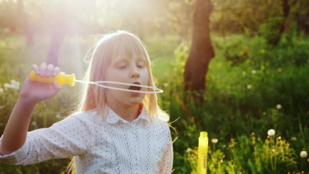 Ein unbeschwertes Mädchen spielt mit Seifenblasen. warmer Frühlingstag. Zeitlupenvideo — Stockvideo