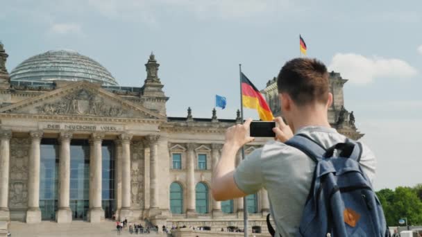 A young tourist man takes pictures of the building of the Bundestag in Berlin. Tourism in Europe and Germany concept — Stock Video