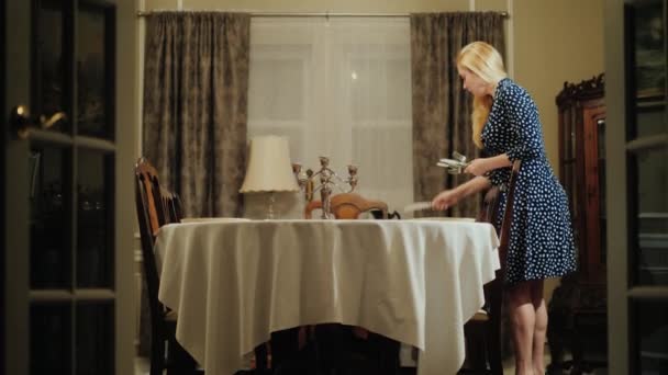 Mladá žena prostře stůl k večeři. Skládá příbory - nože a vidličky — Stock video