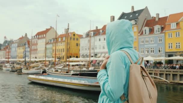Eine Frau schlendert den Nyhavn-Kanal entlang, vor dem Hintergrund berühmter bunter Häuser. — Stockvideo