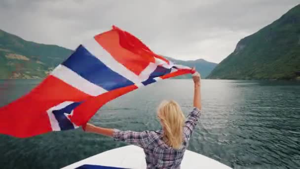 Junge Frau mit norwegischer Flagge auf Fjordkreuzfahrt — Stockvideo