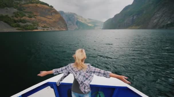 Une femme se tient sur la proue d'un bateau de croisière, profite d'un voyage à travers les fjords de Norvège — Video