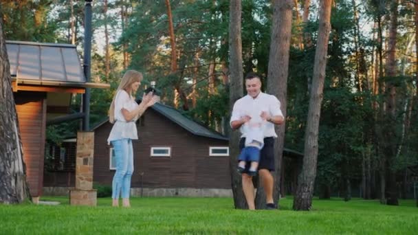 Молода щаслива сім'я грає з дитиною на задньому дворі будинку — стокове відео