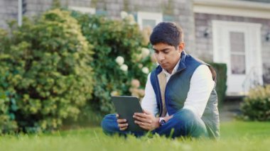 Hintli adam evinin arka bahçesinde bir tablet kullanıyor.