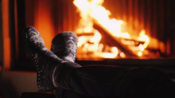 Muž v teplých ponožkách si ohřívá nohy u krbu — Stock video