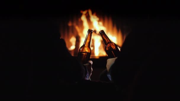 Dva muži odpočívají s lahvemi piva v ruce u krbu a vánoční výzdobou — Stock video