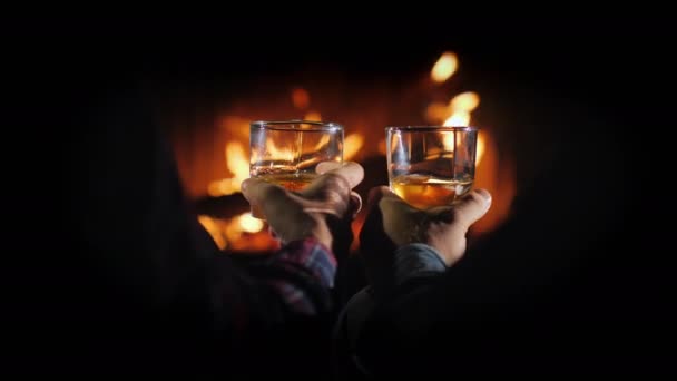 Két férfi kezei egy pohár whiskey-vel a kandalló hátterében, férfi pihenés. — Stock videók