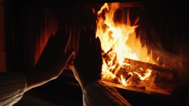 Kadın evdeki şöminenin ateşinde ellerini ısıtıyor. — Stok video
