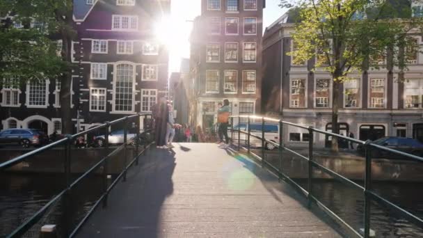 Amesterdam, Netherlands, May 2018: A group of tourists are photographed on a picturesque bridge over a canal in Amsterdam. — Stock Video