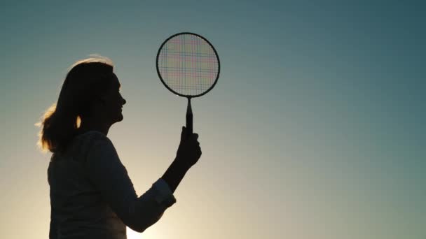 Aktif yaz tatili. Badminton oynayan bir kadın. Güneşte siluet. — Stok video