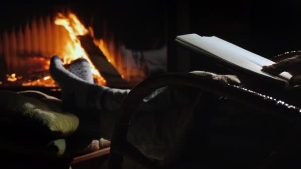 Sentado junto a la chimenea con un cuaderno abierto en una nueva página. Nuevos planes para el Año Nuevo — Vídeos de Stock
