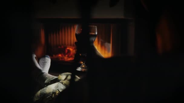 Μια ζεστή βραδιά δίπλα στο τζάκι με ένα ποτήρι κρασί στο χέρι. Χειμερινές διακοπές — Αρχείο Βίντεο