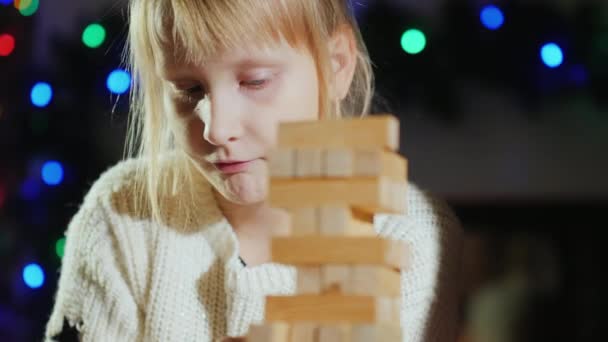 Девушка вытаскивает деревянные блоки из башни - игра для тренировки точности — стоковое видео