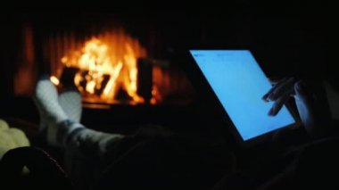 Rahat bir ev ortamında şöminenin yanında bir tablet kullanın