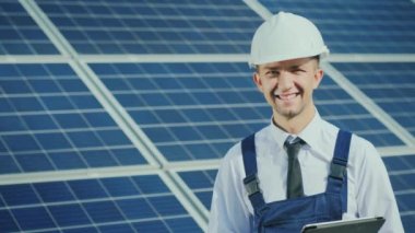 Bir güneş enerjisi istasyonunun arka planında başarılı genç bir mühendisin portresi
