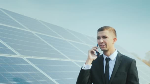 ビジネスマンは太陽光パネルに沿って行き、電話で話す — ストック動画