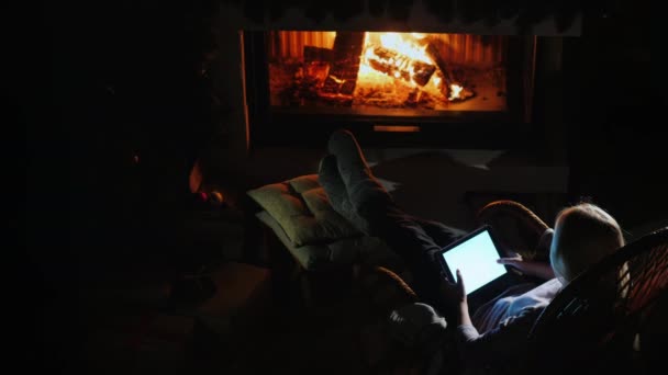 Bir kadın şöminenin yanında dinleniyor, tablet kullanıyor. Yukarıdan görüntüle — Stok video