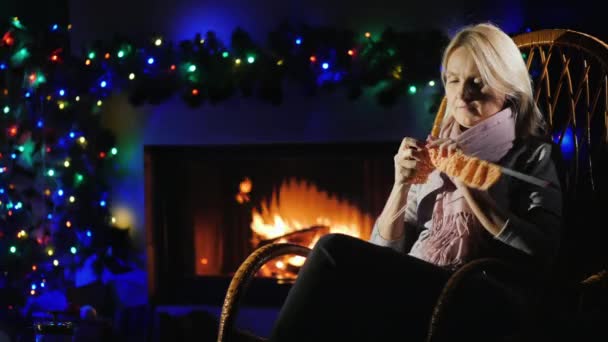 Avond bij de open haard voor Kerstmis - een vrouw breit warme kleren — Stockvideo