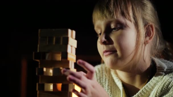 Retrato de un niño jugando un juego donde tienes que sacar bloques de madera de la torre — Vídeos de Stock