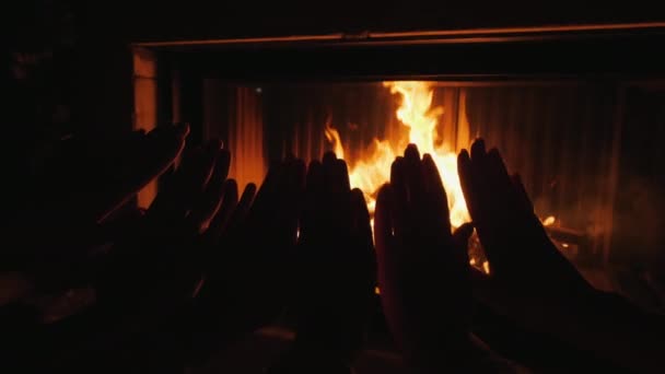 Rodzice z dzieckiem rozgrzewają dłonie ogniem kominka — Wideo stockowe