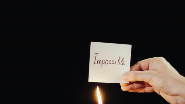 El hombre quema un papel con la inscripción Imposible — Vídeo de stock