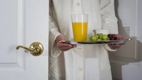 Kobieta trzyma tacę z jedzeniem, stoi przy otwartych drzwiach do pokoju — Zdjęcie stockowe