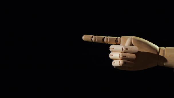 Wooden hand shows the pointer finger direction on a black background — ストック動画