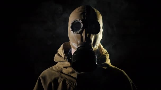Een man in een beschermend pak en gasmasker, rook op de voorgrond — Stockvideo