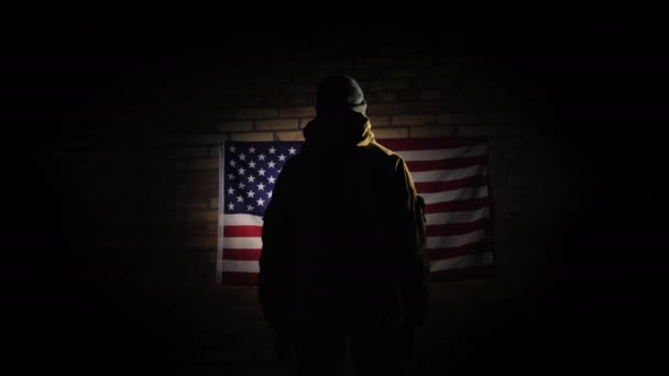 Η σιλουέτα ενός ανθρώπου -- κοιτάζει την αμερικανική σημαία στον τοίχο από τούβλα, η θέα από πίσω — Αρχείο Βίντεο