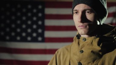 Amerikan bayrağının arka planında genç bir adamın yan görünüşü