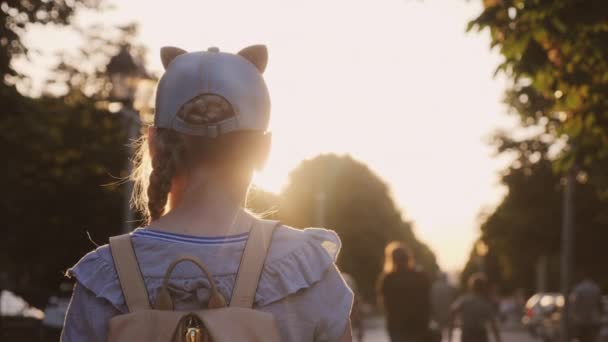 Вид с задней стороны девушки, стоящей в парке, люди проходят мимо — стоковое видео