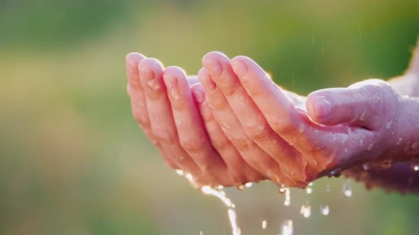 Un hombre trata de retener el agua en sus palmas — Vídeos de Stock