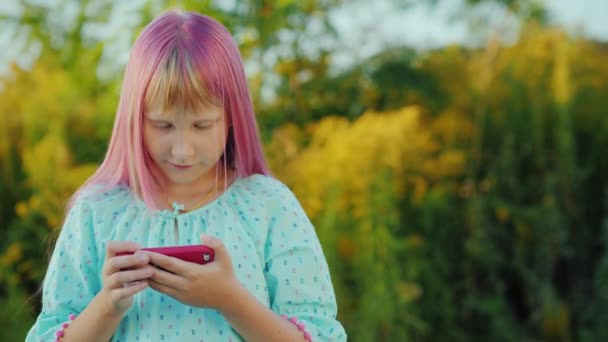 Das Mädchen mit den rosafarbenen Haaren benutzt ein Smartphone im Freien — Stockvideo