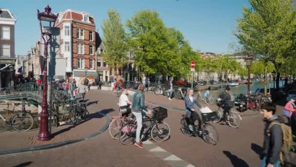 Amesterdam, Nizozemsko, květen 2018: Scénická křižovatka s mostem s hustým provozem jízdních kol. — Stock video