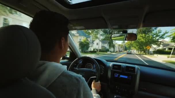 Азиатский мужчина за рулем автомобиля в типичном пригороде США — стоковое видео