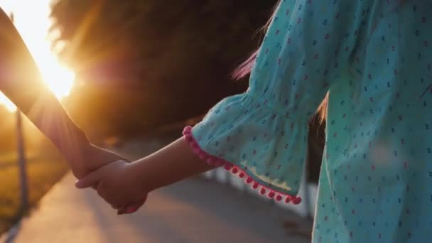 Die Hände einer Mutter und eines Babys, die an der Hand geführt werden. Silhouetten in den Sonnenstrahlen bei Sonnenuntergang — Stockvideo