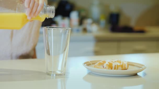 Frukost med juice och croissant, en kvinna häller juice i ett glas — Stockvideo