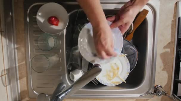 Мужчина моет грязную посуду на кухне, вид сверху — стоковое видео